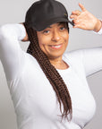 Woman wearing Coils to Locs Kimmie Cap with braids brown. Both hands holding cap in a front view.
