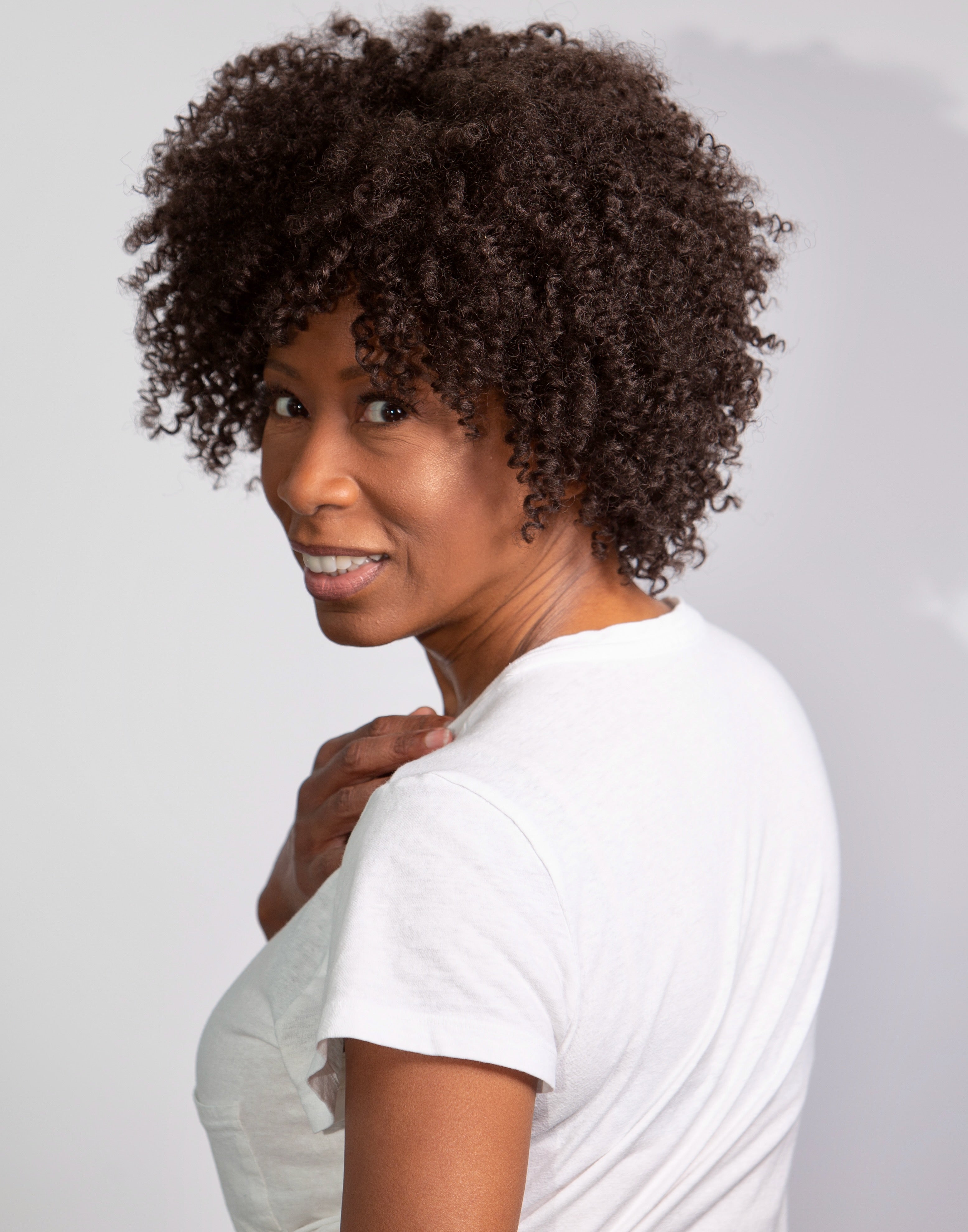 Black woman wearing Coils to Locs Ashanti synthetic wig in dark brown.