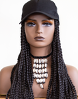 Coils to Locs kimmie cap black front on a mannequin head with a cowerie shell necklace.